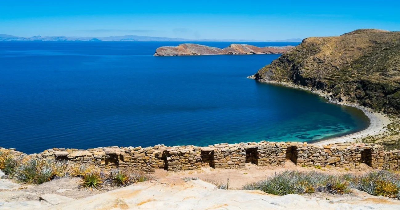 Crystal-clear waters of Lake Titicaca reflecting the surrounding mountains | Andean Travel Experience Crystal-clear waters of Lake Titicaca reflecting the surrounding mountains | Andean Travel Experience