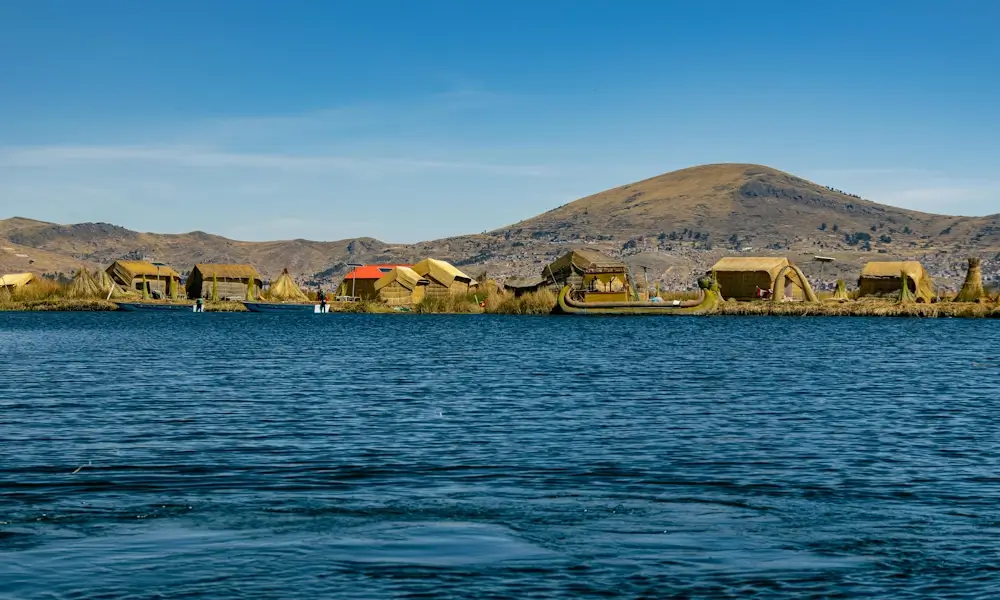 Scenic view of Lake Titicaca in Peru with deep blue waters and surrounding Andean mountains. | Andean Travel Experience Scenic view of Lake Titicaca in Peru with deep blue waters and surrounding Andean mountains. | Andean Travel Experience